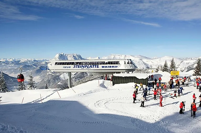 Lyžaři u stanice lanovky Steinplatte Waidring v zimě na slunci