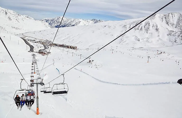 Telesilla en el dominio esquiable de Pas de la Casa con vistas a amplias pistas nevadas y a las montañas.
