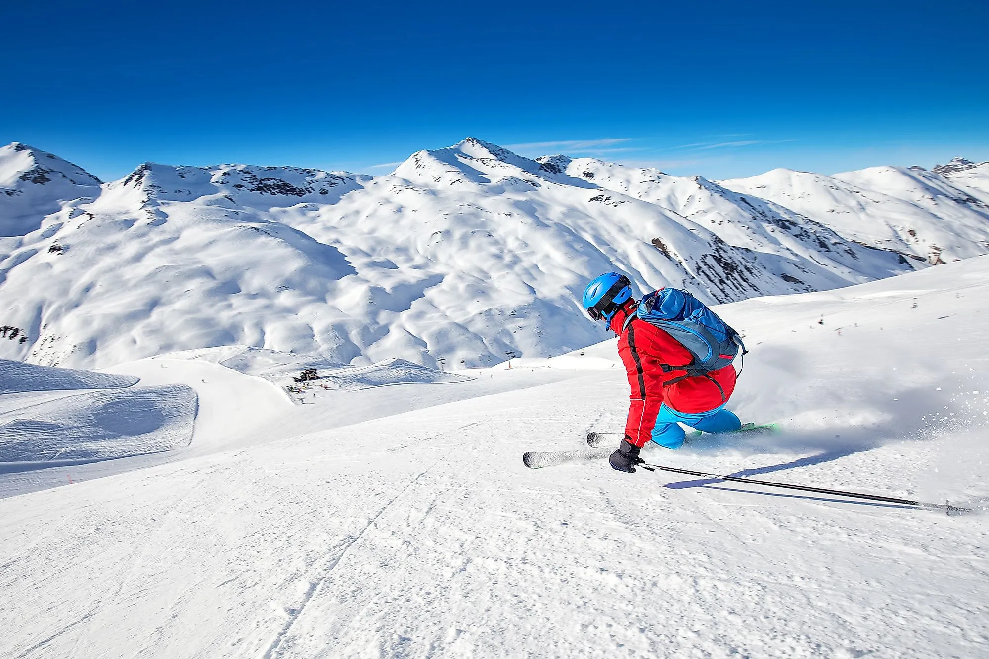Lyžař v Livignu sjíždí bílou sjezdovku na pozadí vysokohorské krajiny