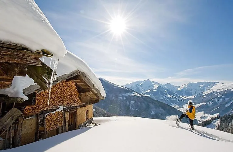 Winterlandschaft bei Alpbach mit Wanderer und verschneiter Hütte in den Alpen