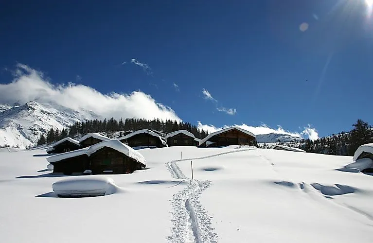 Snow-covered hut landscape in Fiesch-Aletsch with deep snow and a bright blue sky