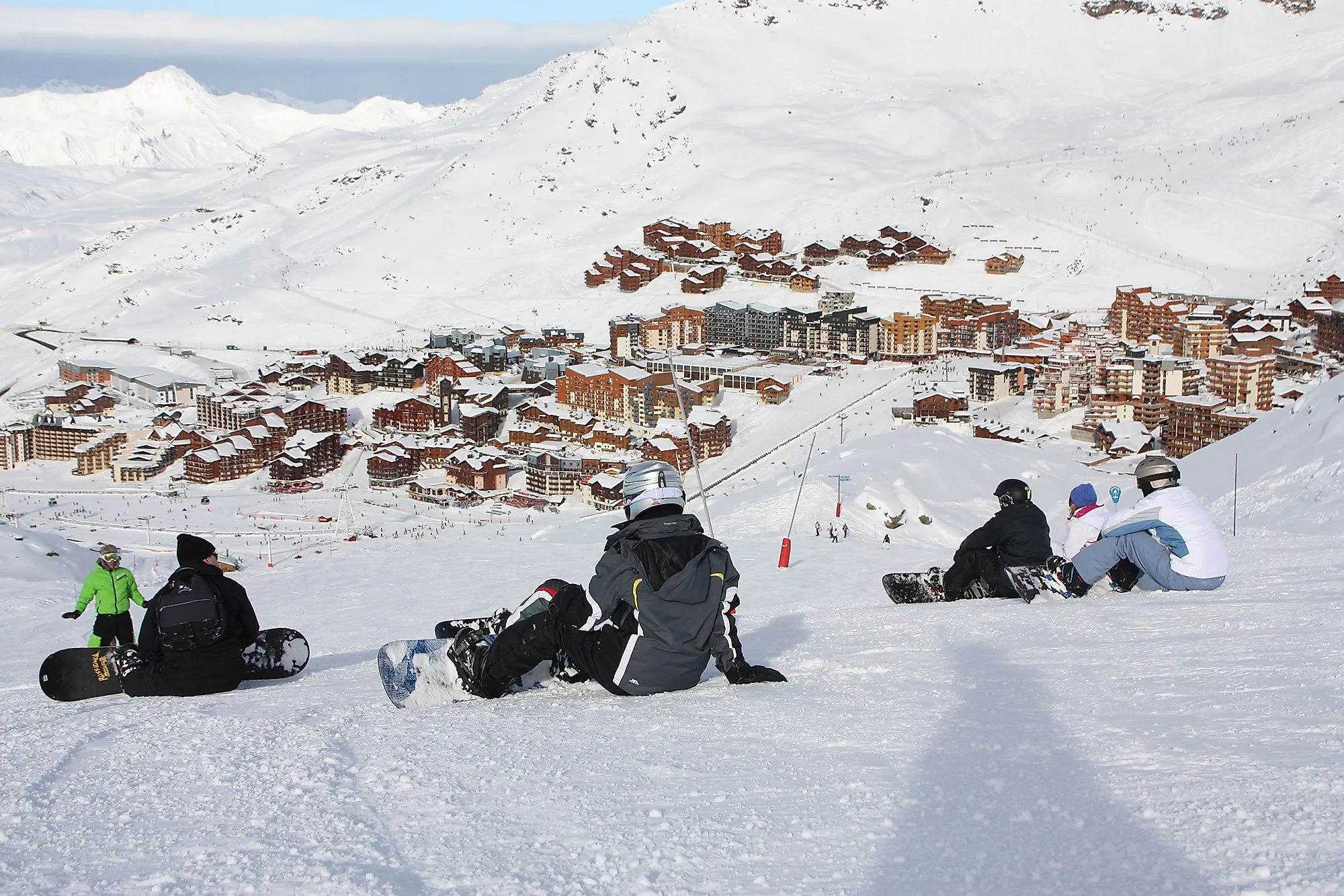 Snowboarder seduti sulla pista con vista sul villaggio sciistico di Formigal nei Pirenei innevati