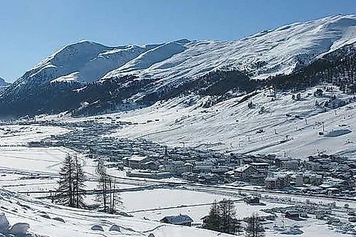Blick auf das tief verschneite Livigno im Winter mit Bergen und Tal unter blauem Himmel