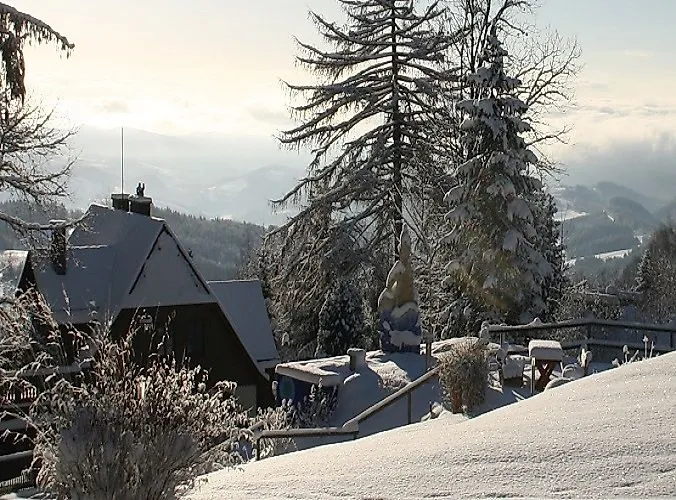 Paysage hivernal enneigé à Mönichkirchen avec des chalets confortables, des arbres couverts de neige et une vue lointaine sur la vallée.