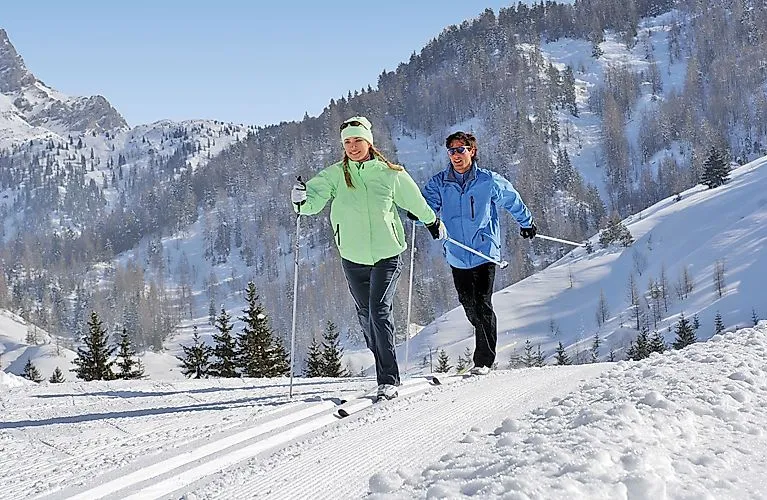 Two cross-country skiers enjoy sunny winter weather on the trail near Windischgarsten.