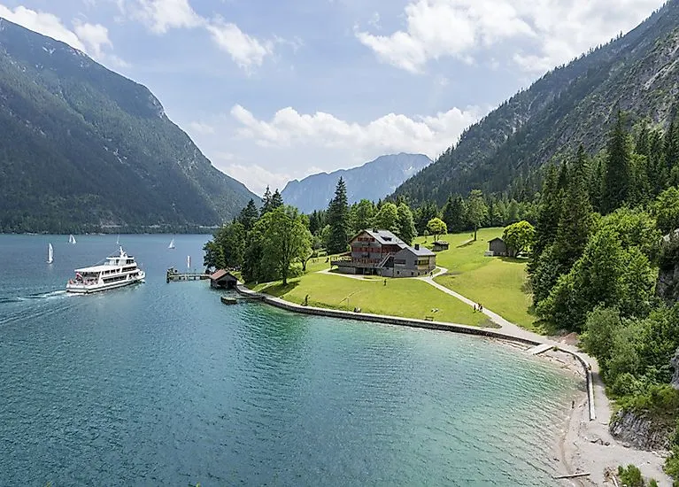 Výletní loď kotví na slunném břehu Achenkirchu u jezera Achensee v Tyrolsku.