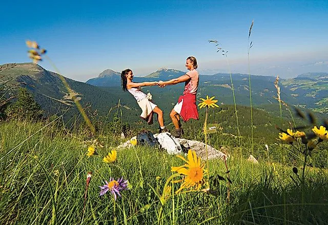 Coppia che si gode una pausa escursionistica su un prato alpino con vista sulle montagne a Obereggen, in Alto Adige