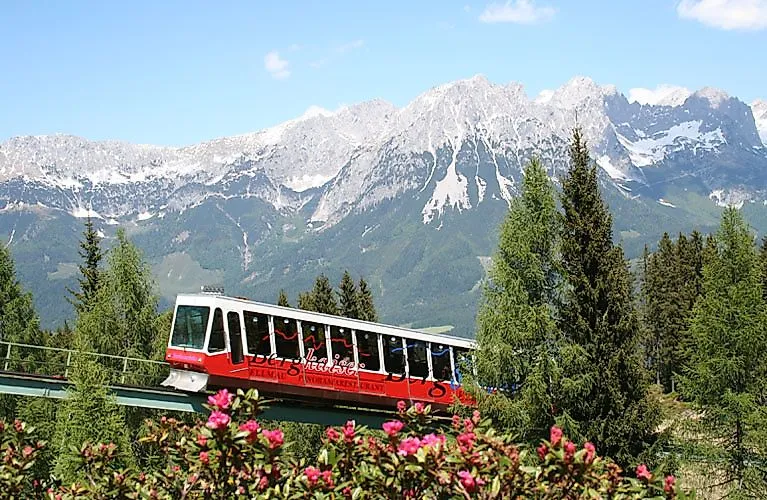 Červená panoramatická lanovka premáva v lete na pôsobivom horskom pozadí na vrchole Wilder Kaiser.