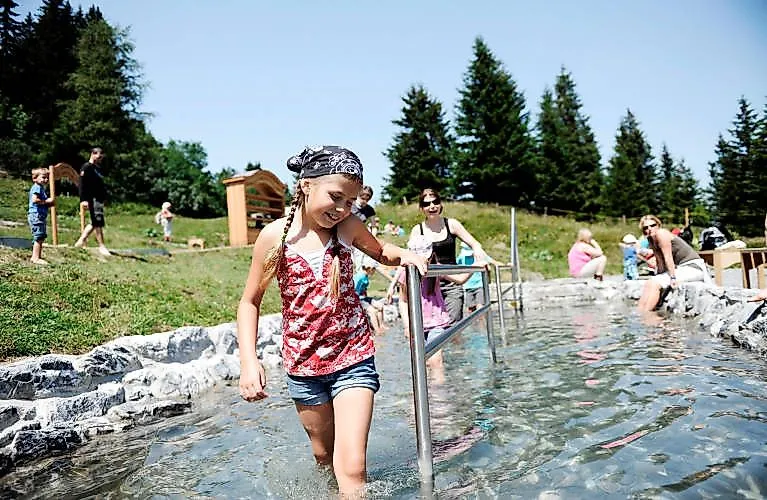 Dívka běží se smíchem přes kaluž vody na hoře Wangs-Pizol