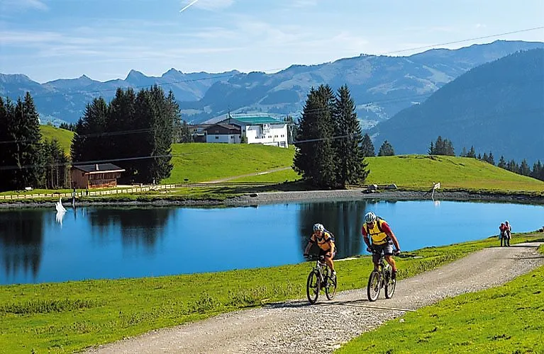 Ciclistas en un sendero de verano con vistas a las montañas y a un lago cerca de Ellmau, en la región de Wilder Kaiser.