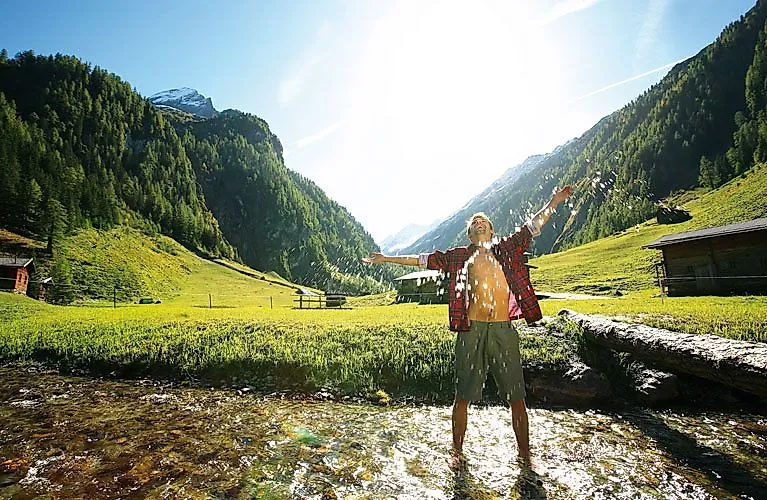 Gli escursionisti si godono l'acqua fresca di sorgente in una soleggiata valle alpina vicino a Gerlos, incastonata tra le montagne alpine della Zillertal
