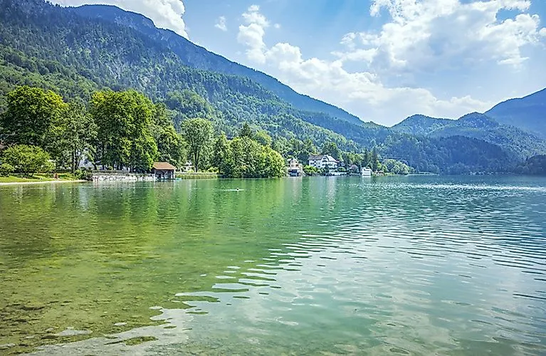 Summer view of the clear Kochelsee with surrounding forest and mountains in Bavaria.