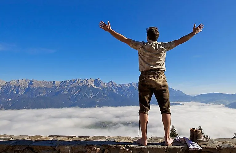Turista naboso si užívá výhled na salcburské hory nad mořem mlhy nedaleko Saalfeldenu Leogang.