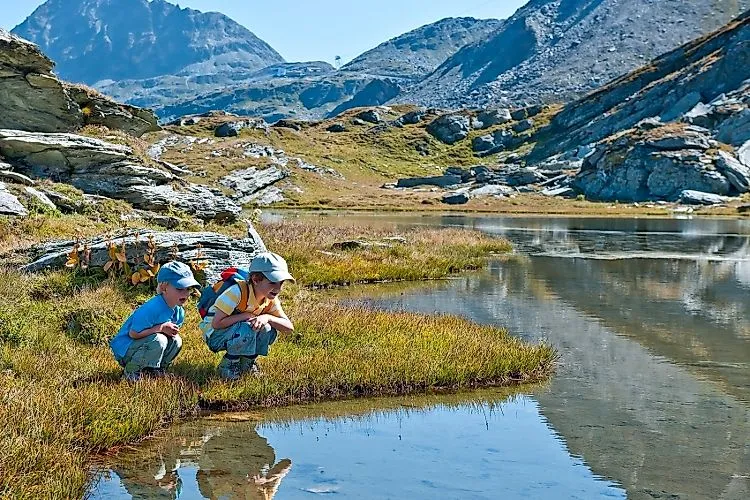 Deux enfants découvrent un lac de montagne clair dans un paysage d'été alpin
