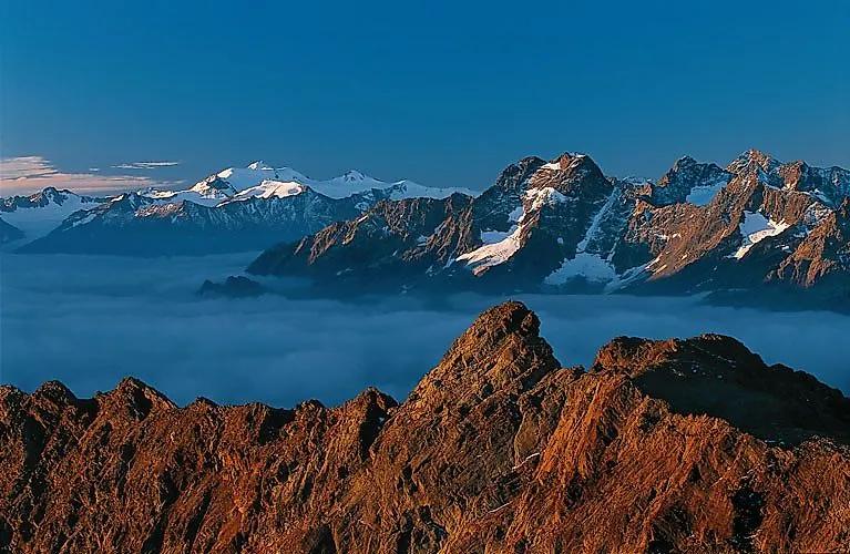 Sonnenaufgang über der Bergkette in Sölden mit beeindruckendem Blick auf schneebedeckte Gipfel und Wolkenmeer.