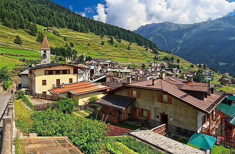 View of Pejo in summer with church, mountain village and green terraced landscape in Val di Sole