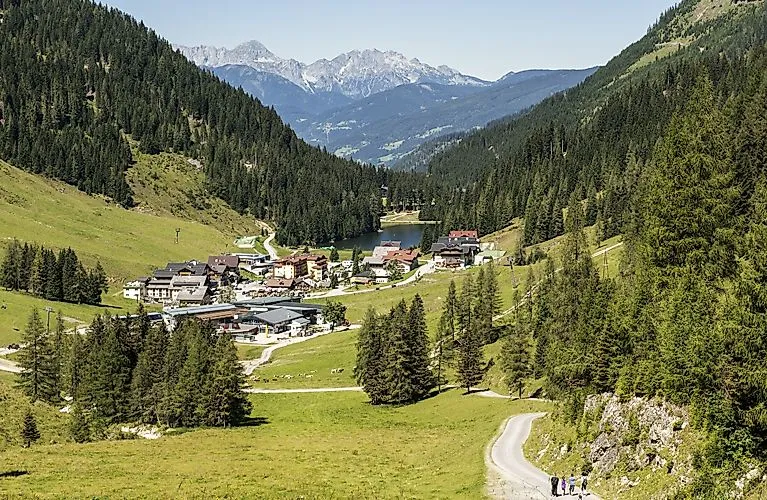 Letní panorama Zauchensee s horskou vesnicí, zelenými alpskými pastvinami a turistickými stezkami