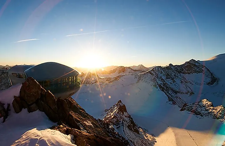 Amanecer sobre el glaciar Pitztal con estación de montaña futurista en un paisaje de alta montaña nevado